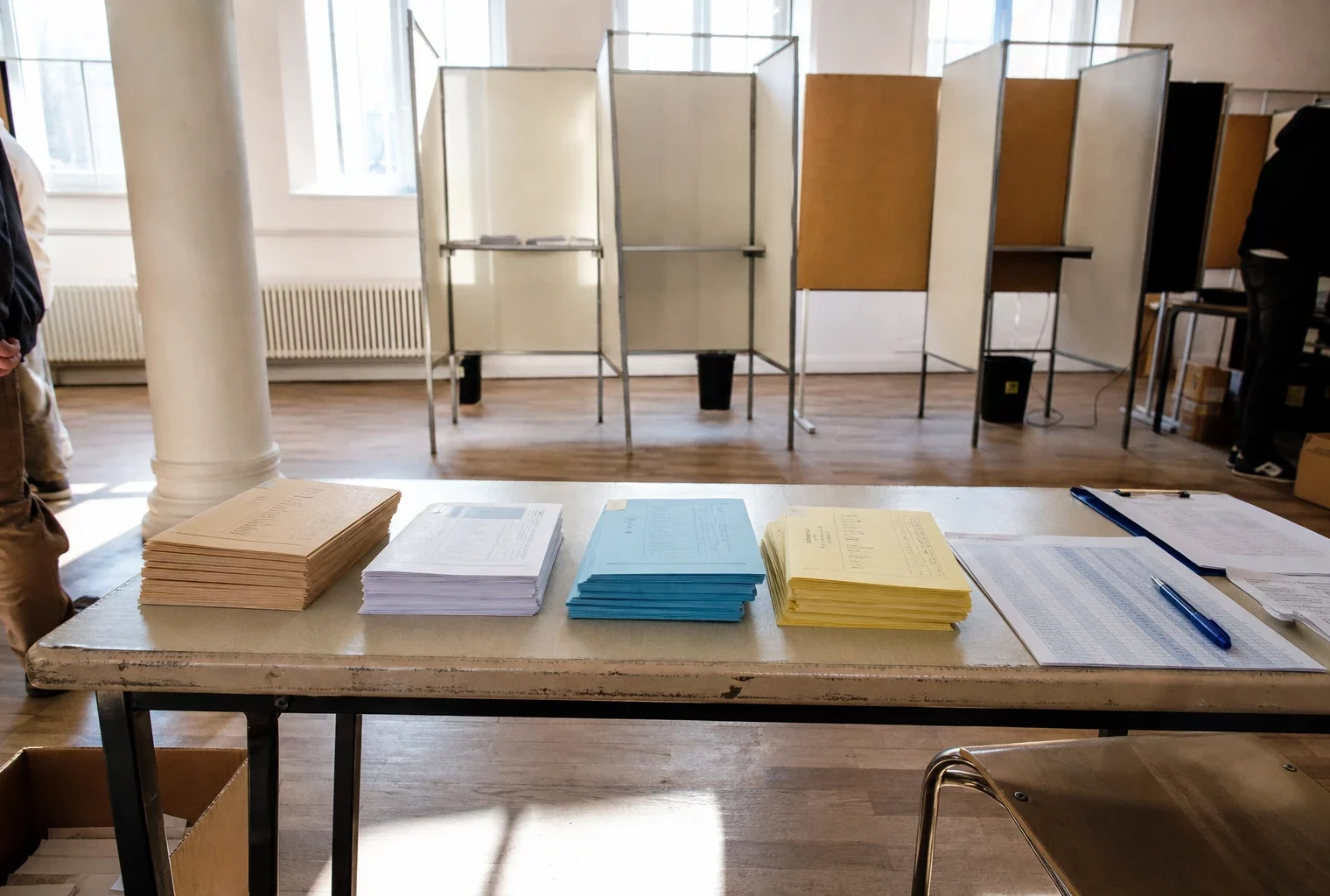 Bureau de vote d’une primaire de gauche avec bulletins, table d’émargement et matériel électoral.