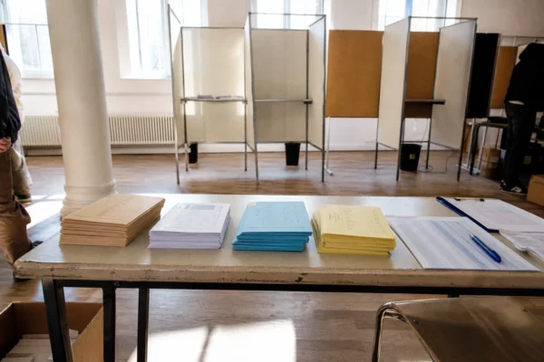 Bureau de vote d’une primaire de gauche avec bulletins, table d’émargement et matériel électoral.