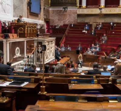 Rangées de pupitres parlementaires équipés de microphones et de dispositifs de vote dans une salle de séance.