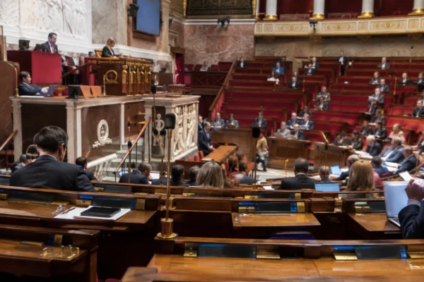 Rangées de pupitres parlementaires équipés de microphones et de dispositifs de vote dans une salle de séance.