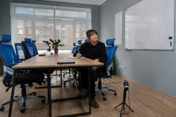 Salle de réunion associative en France, table centrale, chaises, carnet et téléphone, avec matériel d’enregistrement discret.