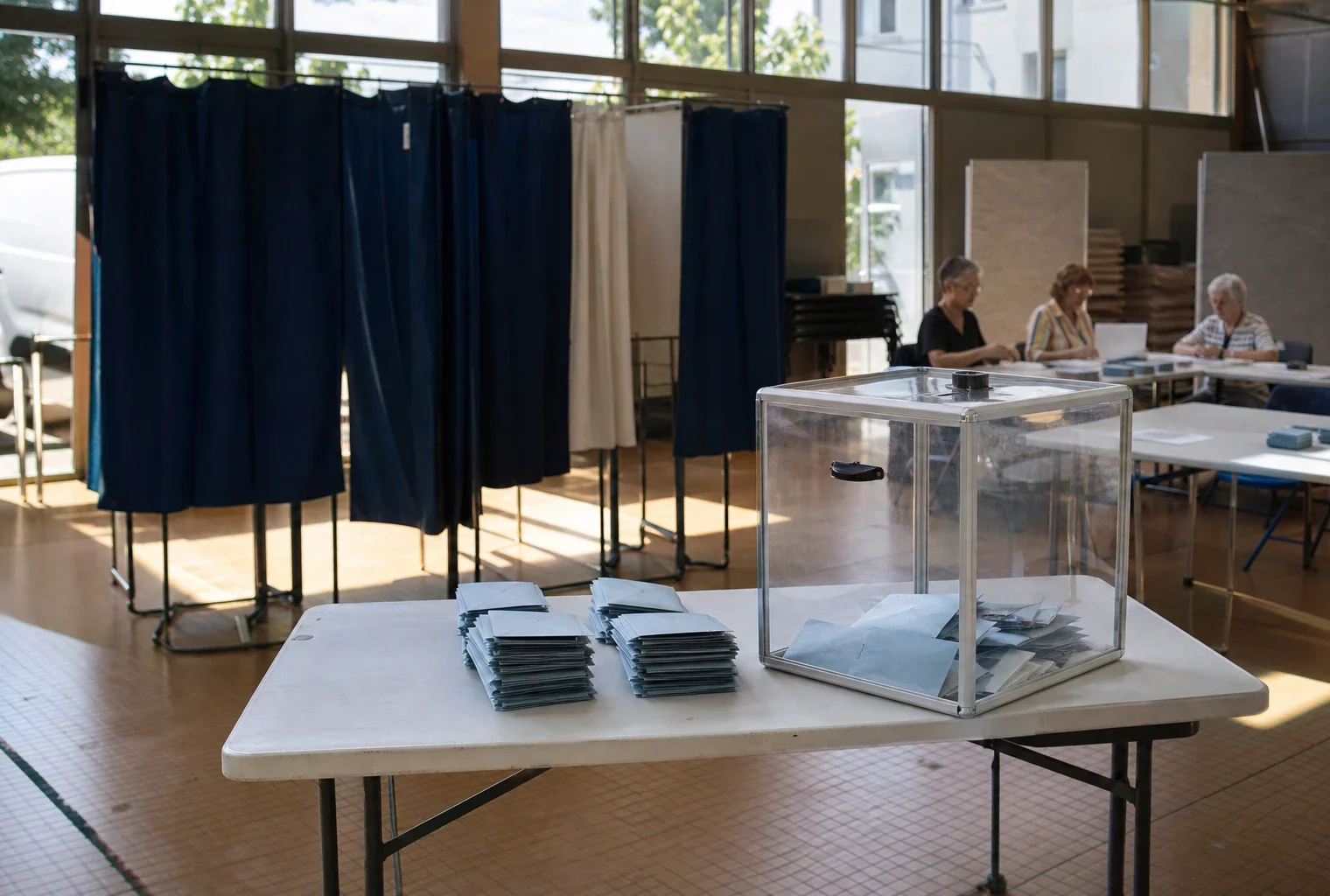 Bureau de vote municipal avec isoloirs, urne transparente et bulletins de vote, à Romilly-sur-Seine.