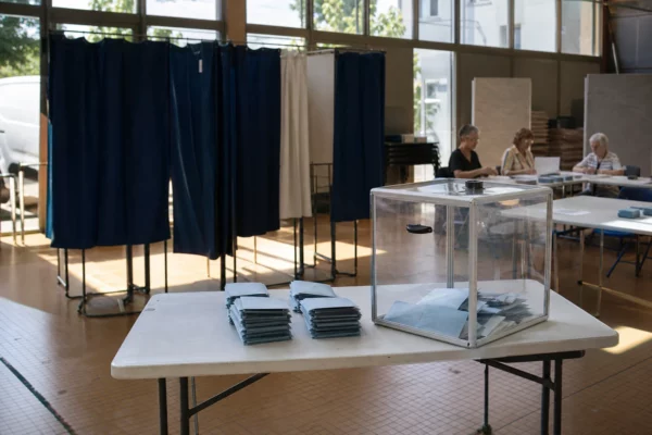 Bureau de vote municipal avec isoloirs, urne transparente et bulletins de vote, à Romilly-sur-Seine.