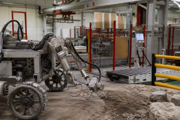 Robot de prospection lunaire en test dans un atelier spatial français, sur sol technique avec câbles et structures industrielles.