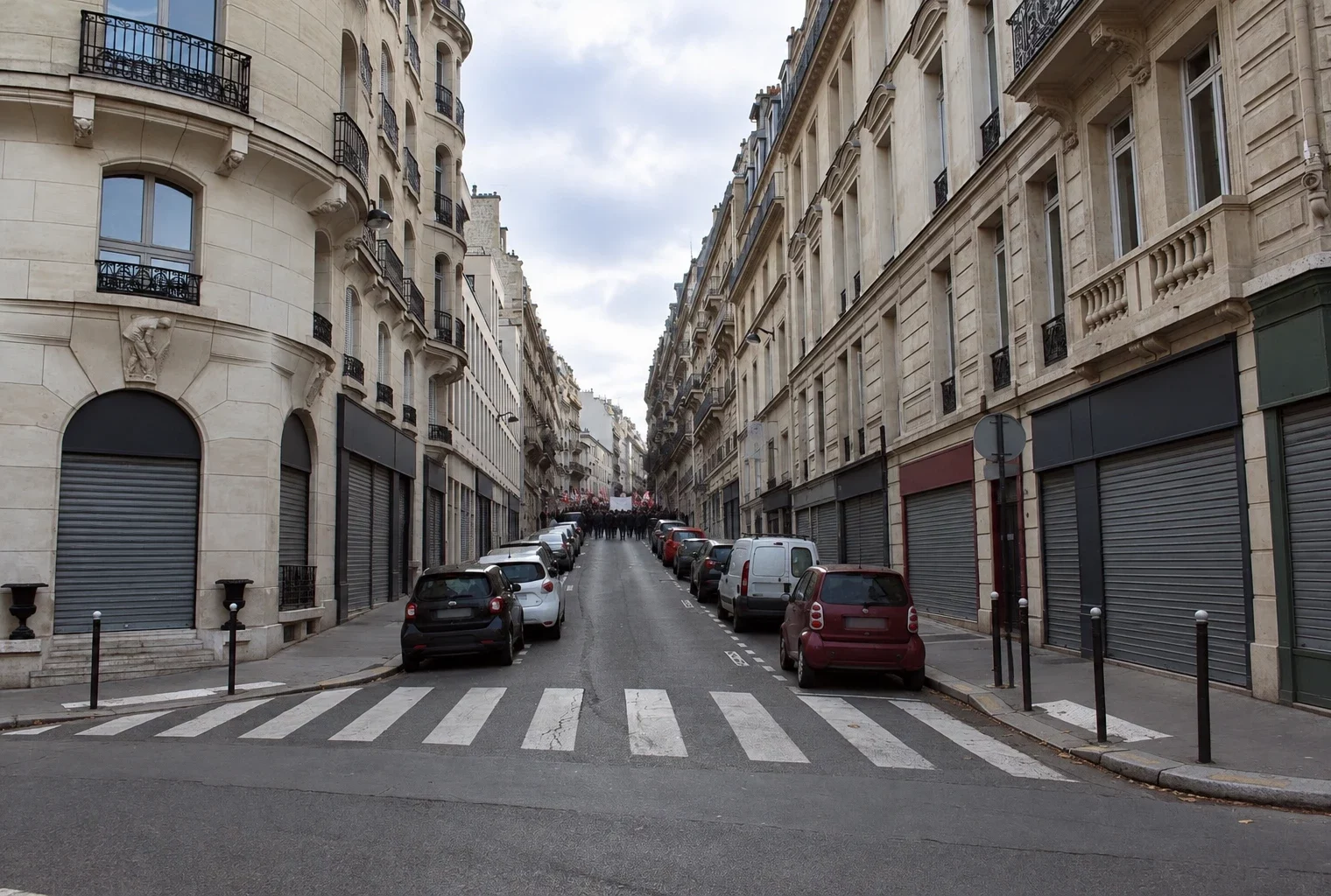 Rue commerçante aux façades anciennes et vitrines fermées, bordant un itinéraire de manifestation dans une ville française.