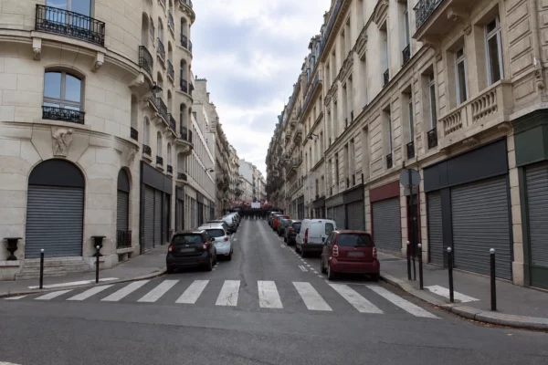 Rue commerçante aux façades anciennes et vitrines fermées, bordant un itinéraire de manifestation dans une ville française.