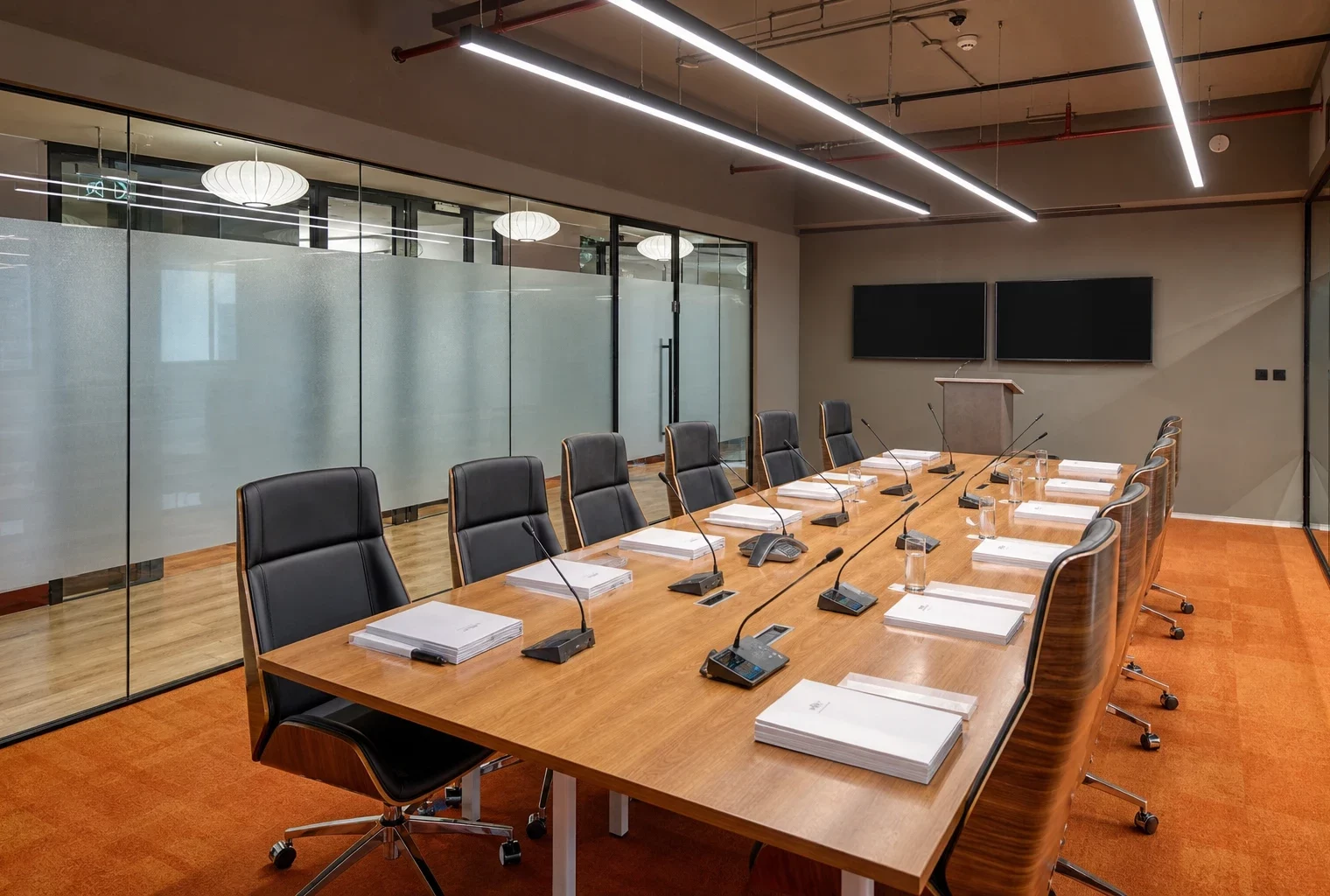 Salle de réunion moderne de la BCE à Francfort, table centrale, micros alignés et écrans éteints sous la lumière du matin.