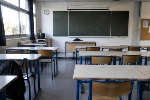 Salle de classe de lycée vide, avec des tables d’élèves alignées face au tableau et aucune personne présente.