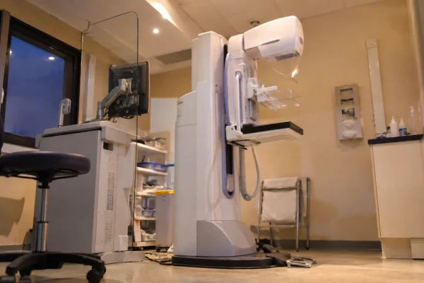Un mammographe et son poste de commande dans une salle d’imagerie médicale aménagée pour le dépistage du cancer du sein.