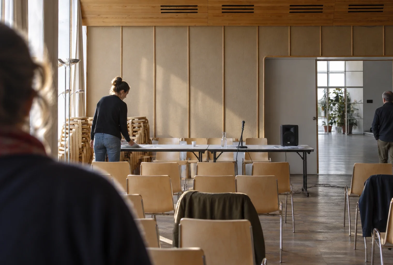 Salle de réunion en préparation, avec chaises empilables, tables pliantes et équipement de sonorisation dans un tiers-lieu.