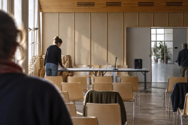 Salle de réunion en préparation, avec chaises empilables, tables pliantes et équipement de sonorisation dans un tiers-lieu.
