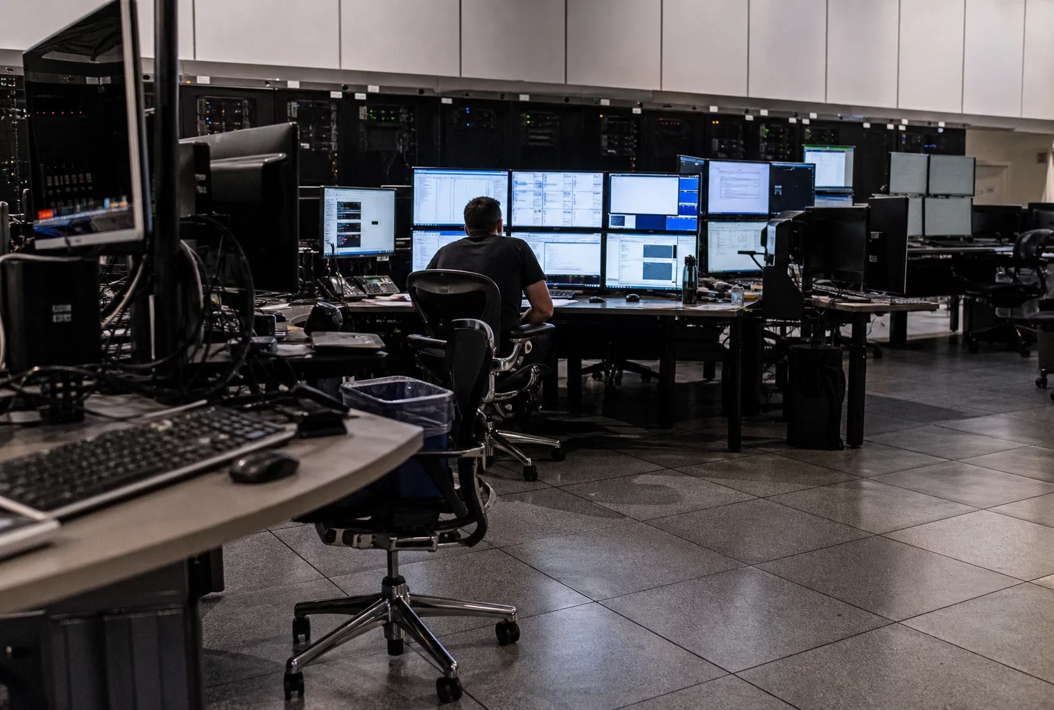 Salle de supervision informatique avec écrans et postes de travail, évoquant les outils d’analyse de données des services de sécurité.