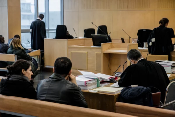 Salle d’audience d’un tribunal judiciaire avec dossiers et bancs vides, pour illustrer la procédure de reconnaissance de filiation.