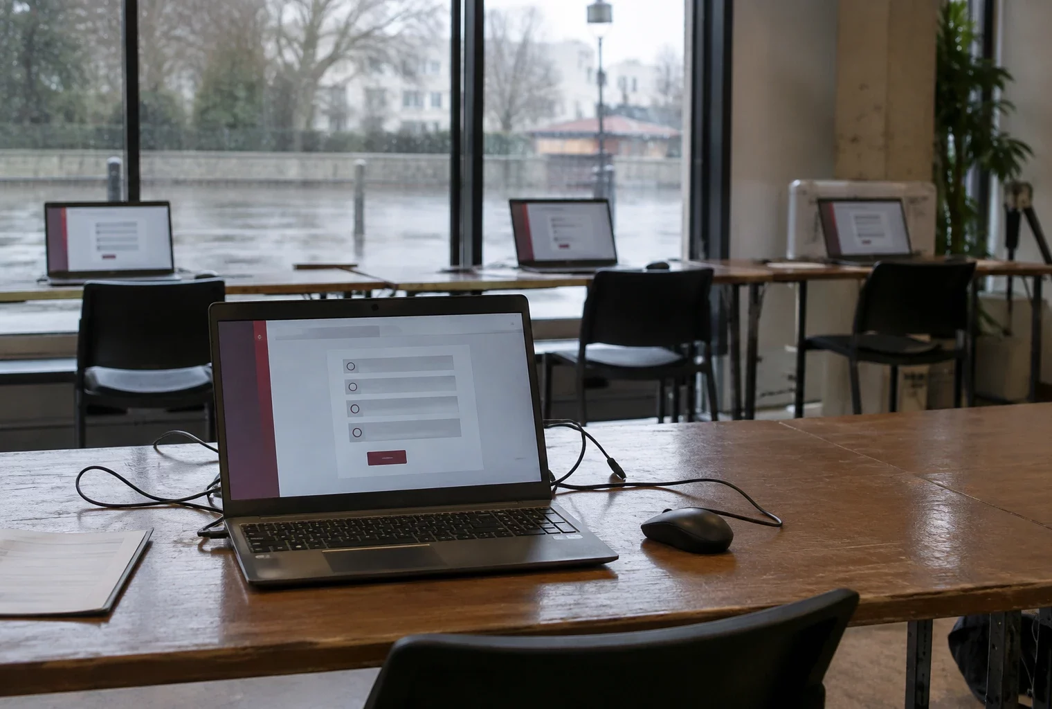 Un ordinateur portable affiche une interface de vote en ligne, avec d’autres postes informatiques installés dans la pièce.